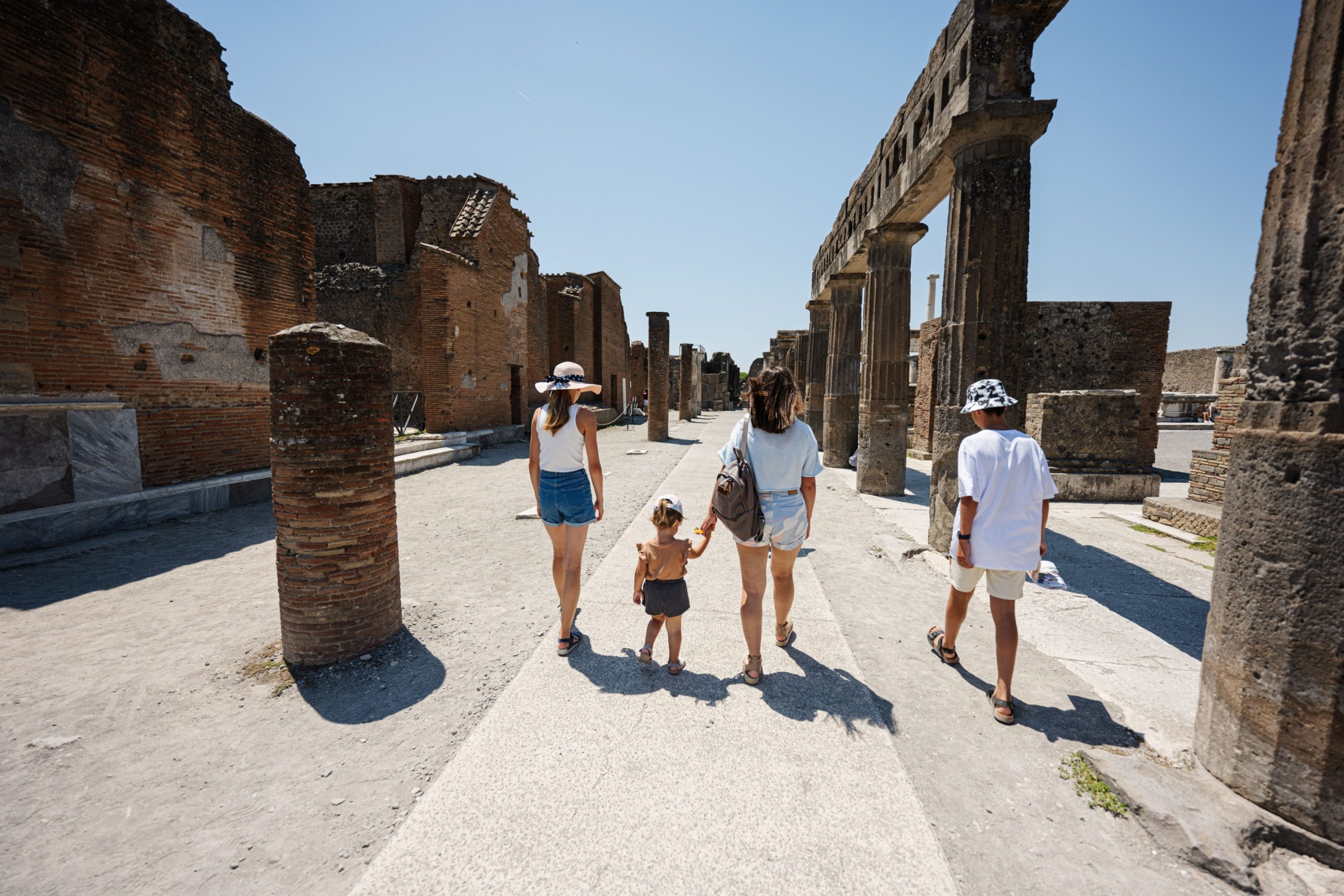 Family with children walking the ancient streets of Pompeii, Italy